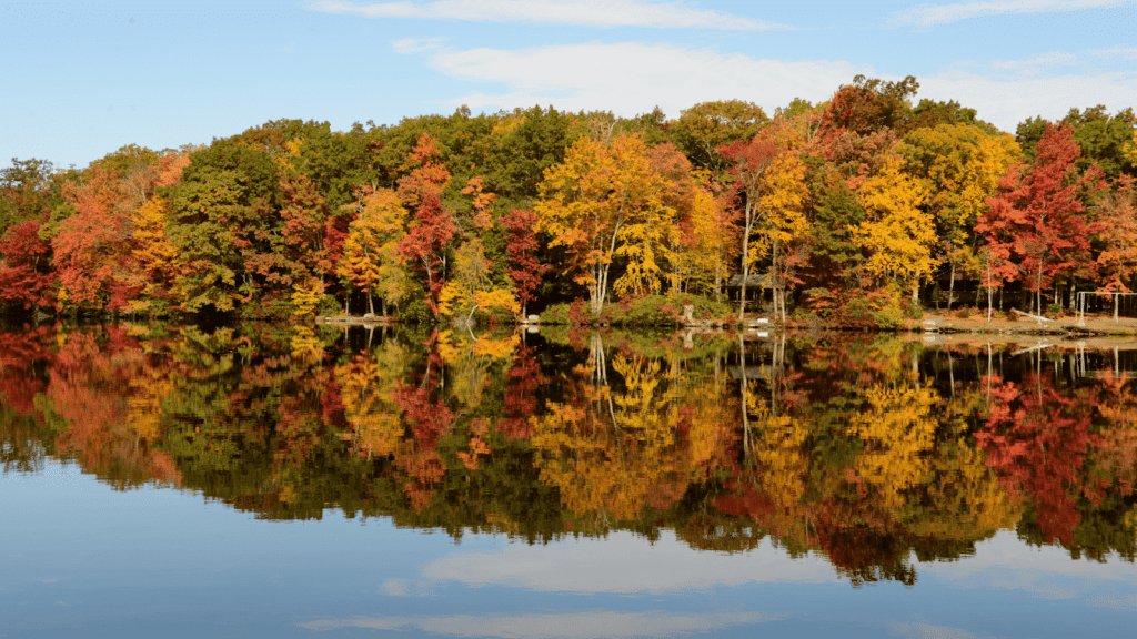 Fall colors reflected in a Poconos lake with trees in vibrant reds and yellows.