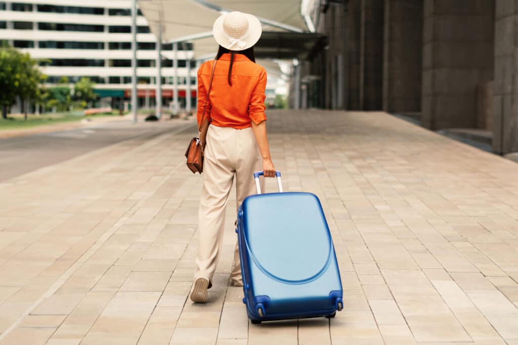 Lady Walking With Big Blue Suitcase Bag Near Modern Airport