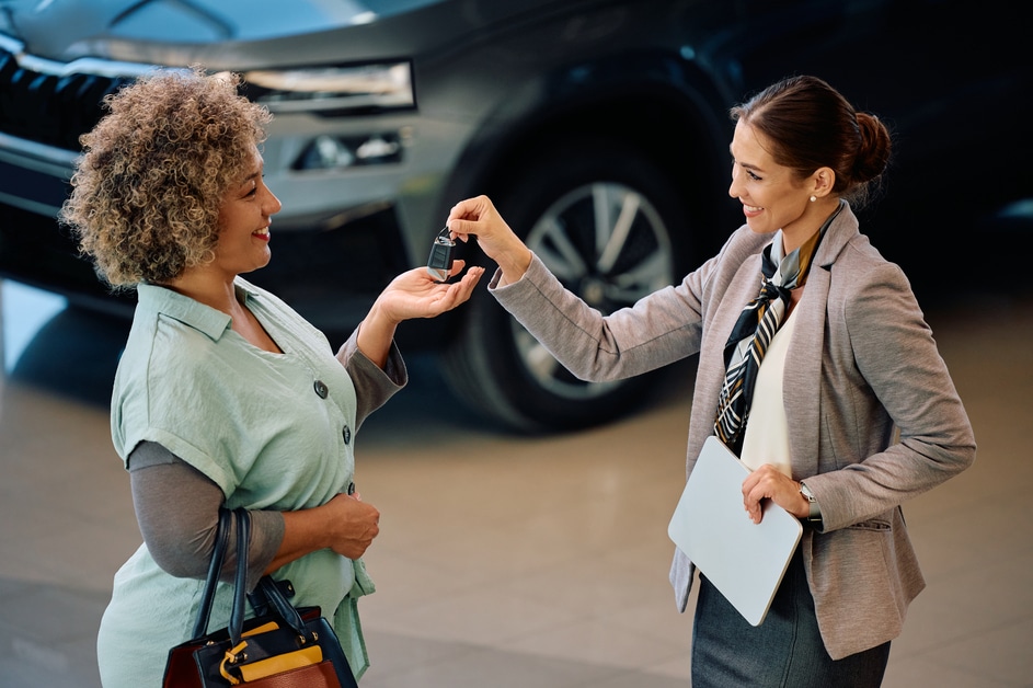 Happy African American woman getting keys from saleswoman