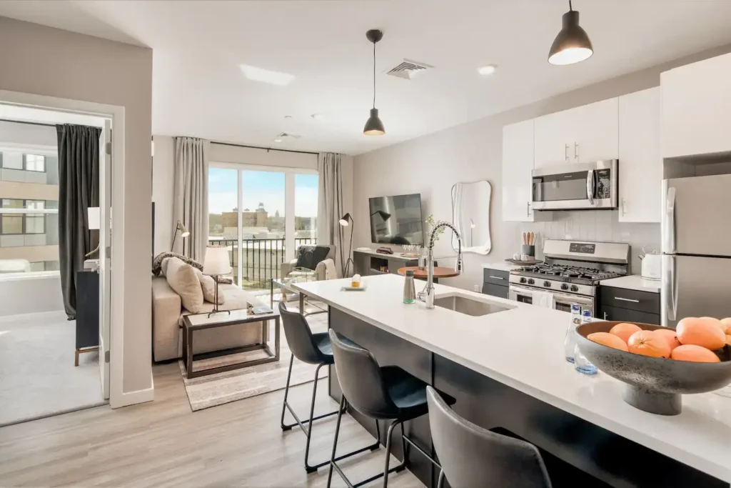 Open-concept kitchen and living area with stainless steel appliances and city view – Hyatus Living rental.